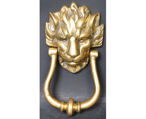 A large vintage 20th century brass lions head door knocker in the form of a lions head with cast features and swan neck style