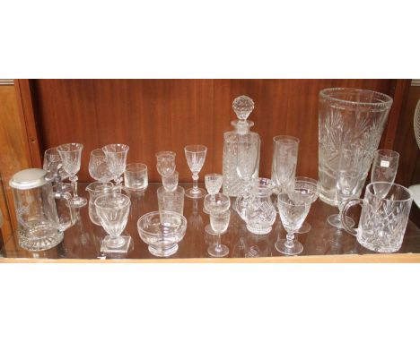 A shelf of assorted glasswares including a decanter, large vase, metal-topped glass Stein, tankard, sherry glasses and champa