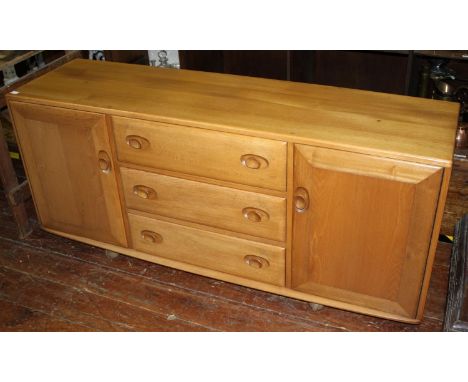 An Ercol light elm 'Windsor' sideboard, with three central graduated drawers, flanked by two cupboards and raised on castors,
