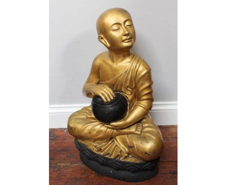 A large gold and black painted composite figure of a seated Buddha head raised looking left, holding a bowl on lotus leaf bas
