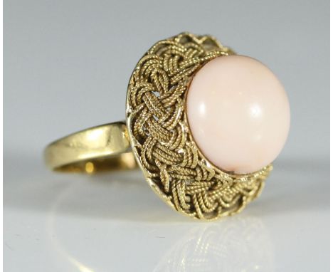 An 18ct gold ring set with a cabochon coral in plaited mount, gross weight approximately 7.6g 