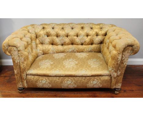 A drop-end Chesterfield style sofa, with gold, floral fabric upholstery, raised on bun feet to castors, 164cm wide 