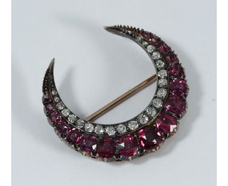 A Diamond Ruby and Gold Brooch/Pendant, in unmarked yellow gold, of crescent design and set with 22 graduated Victorian-Cut d