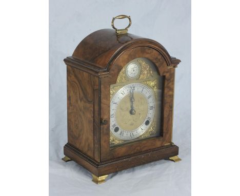 A mantel clock by 'Elliott', the brass dial with scrolled, floral engraved decoration, applied decorative masks and retailers