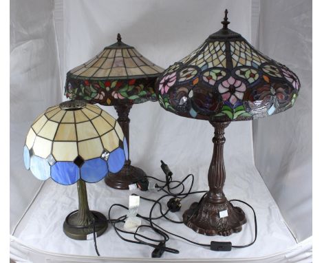 Two various large Tiffany style lamps decorated with stylised flowers, together with a smaller blue and cream lamp with scall
