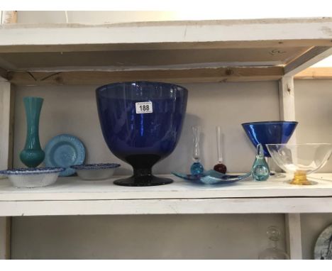 A shelf of glass items including a large Bristol blue vase/glass