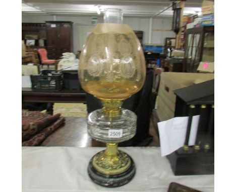 A Victorian oil lamp with glass font and acid etched amber glass shade.