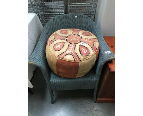 A Lloyd Loom chair and leather pouffe