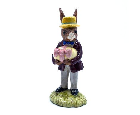 Bunny dressed for Easter holding an egg with ribbon.Hand painted maroon coat, light grey trousers, blue bowtie, yellow straw 