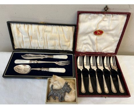 Boxed cake forks, boxed Mother of Pearl handled spoon knife and fork and a dog brooch.