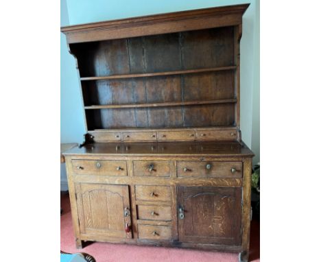 An oak dresser with raised back base with 3 drawers over 2 cupboards and 3 central drawers. Back with four small drawers. 147