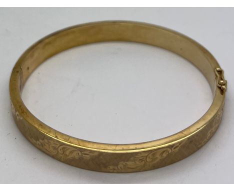 A 9ct gold hinged bangle with engraved decoration. 18gm.Condition ReportGood condition.