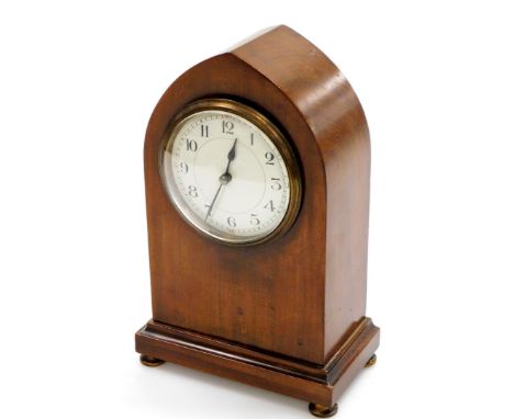 An Edwardian walnut cased mantel clock, with small circular enamel dial, on a stepped base with brass button feet, 23cm high,