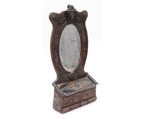 A late 19thC carved oak wall mounted mirror shelf, the curved top above Medussa head and shell carving, with box bottom and t