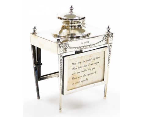 An early George V silver ink stand of neo classical design, having a raised inkwell on a four leg stand, with urns, oval pate