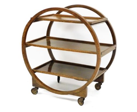 An Art Deco three tier tea trolley, the sides shaped as a circle holding three shelf section on castors, 78cm high, 74cm wide