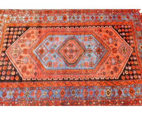 A Middle Eastern carpet, on a red ground with blue medallion border on a central single medallion central panel, on white tas