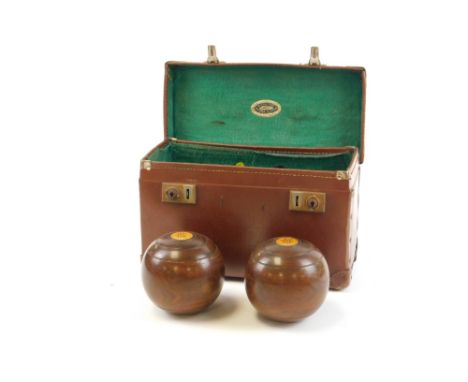 A cased set of carpet bowls, each carved wood detailed with crest emblem, in leather green lined case, marked Lehna Vulcan. 