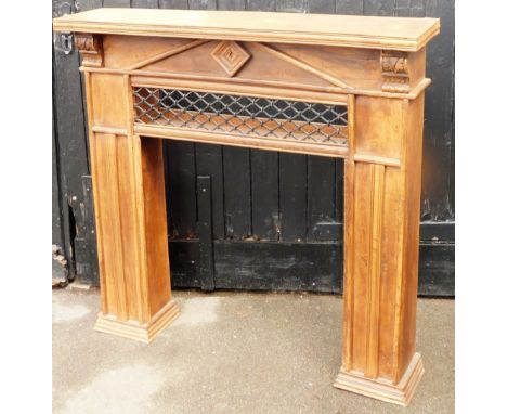 An oak fireplace surround, with carved leaf finials and metal cross section, on two plinth columns, 125cm high, 125cm wide, 3