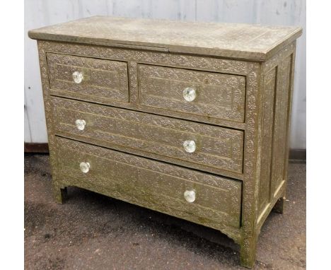 An Eastern style chest of drawers, with inset silver coloured panels, heavily embossed with flowers, with two short and two l