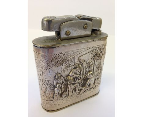 A silver metal cased Dutch style table top cigarette lighter with repousse decoration of figures outside an inn.