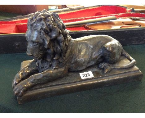 A bronzed model of a resting Lion by R Moll.
