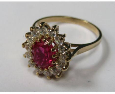 9ct GOLD DRESS RING SET WITH CENTRAL RUBY COLOURED STONE SURROUNDED BY CLEAR STONES 