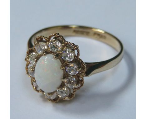 9ct GOLD DRESS RING SET WITH CENTRAL OVAL OPAL SURROUNDED BY SMALL CLEAR STONES 