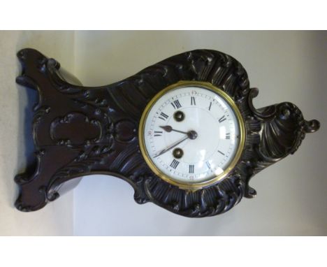 A late 19th/early 20thC Continental canted design, mahogany cased mantel clock with carved and applied asymmetric foliate scr