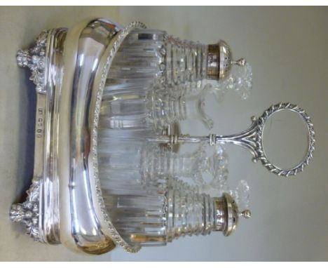 A George IV silver cruet, the carrier of oval ogee form, having a gadrooned rim and a central ring handle, on a wooden platfo