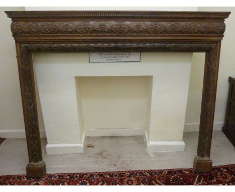 A 19thC mahogany fire surround, the shelf top with a dentil moulded, foliate and scroll carved frieze, the aperture carved wi