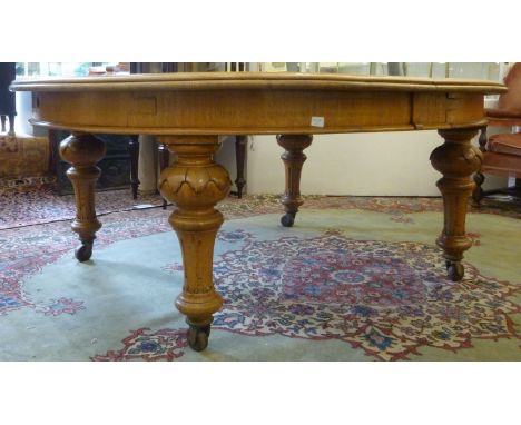 A late Victorian light oak wind-out dining table, the oval top featuring two D-ends with a thumb moulded border, raised on su