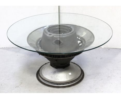 A revolving glass-top occasional table, the base formed from the engine of a Vulcan bomber, diameter 93cm.