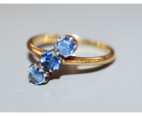 A three-stone light blue sapphire ring, 18ct yellow gold setting, size L.