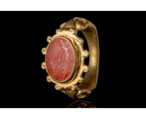 Ca. AD 100 - 300.A carnelian intaglio depicting a seated crowned god resting on a podium, holding a long tool in his right. B