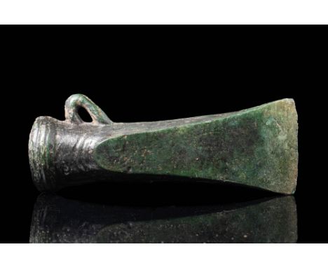 Ca. 1200 - 800 BCA Bronze Age socketed axe head, featuring a corded band around the socket and a small loop at its base. The 