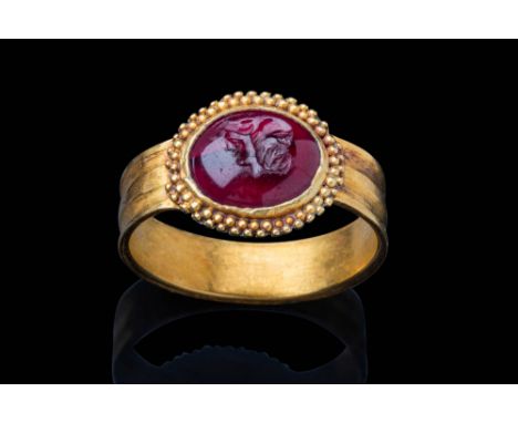 Ca. AD 1 - 200.A carnelian intaglio depicting a gryllos motif, featuring two conjoined heads facing opposite directions. The 