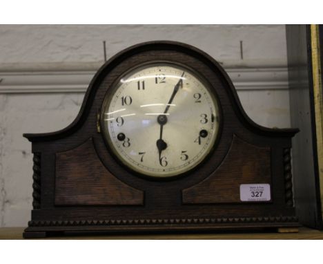 An early 20th century oak-stained dome-top mantle clock, circular dial, Arabic numerals, rope twist supports on a stepped bas