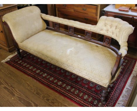 A Victorian mahogany chaise lounge with button-back fabric upholstery with carving and fret work to the mahogany frame on cir