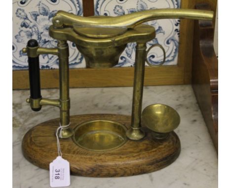 A vintage brass citrus squeezer on an oval oak stained base, 20cm x 28cm