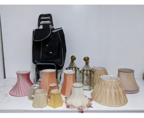 Two brass effect framed and glass panelled lantern lights, mixed fabric light shades and a shopping trolley on wheels, Locati