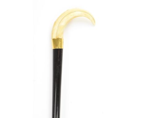 An Edwardian ebonised walking stick, with a warthog tusk handle, brass bound collar and a tapered shaft, 93.5cm longLocation: