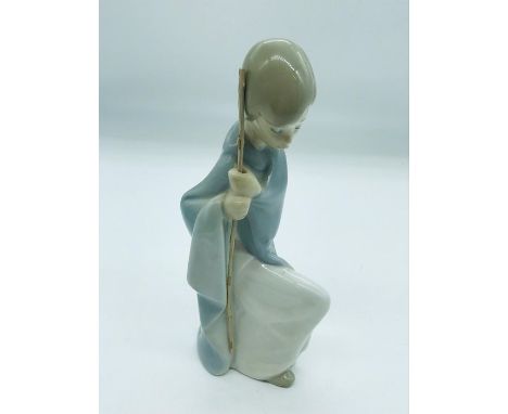 Lladro figurine of a young boy kneeling holding a stick