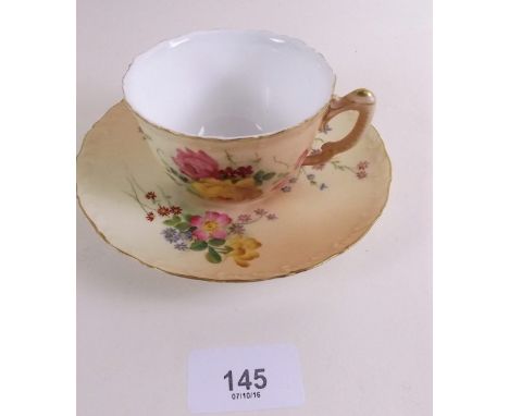 A Royal Worcester cup and saucer painted flowers on an ivory blush ground 