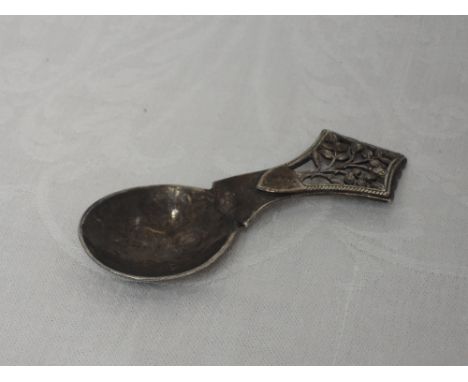 An Arts & Crafts style silver caddy spoon having a hammered bowl and terminal bearing pierced decoration in the form of the T