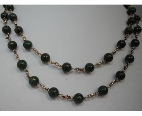 A long string of dark green jade style beads with yellow metal chain links and clasp stamped 9ct, approx 38' long