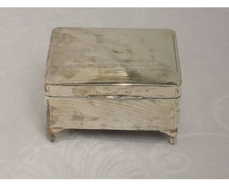 A silver cigarette box having engine turned decoration with plain cartouche and bracket feet, Birmingham 1930, W G Sothers Lt