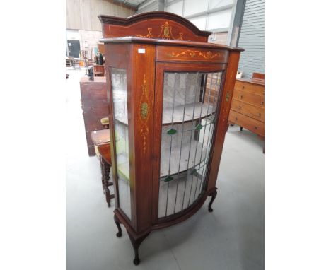 An Edwardian mahogany display cabinet having arch ledge back with coloured leaded bow glass front, with inlay decoration and 