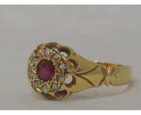 A lady's dress ring having a central ruby within a rough cut diamond chip set star mount to moulded shoulders on a 22ct gold 