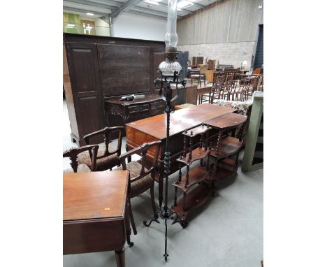 An early 20th century black wrought iron oil lamp torchere having glass reservoir to top and trefoil legs